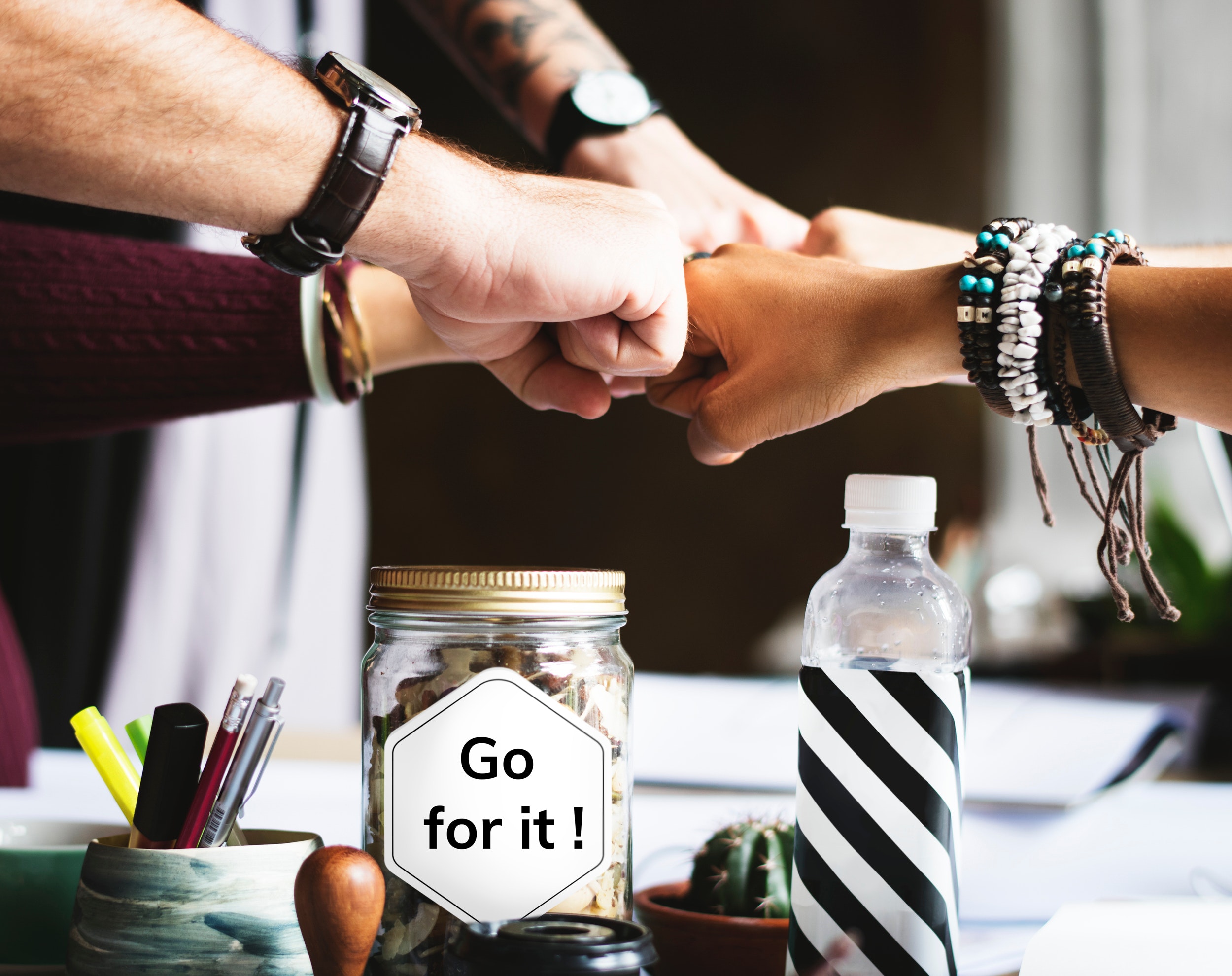 ASuperior team spirit symbolized with hands joined over a jar